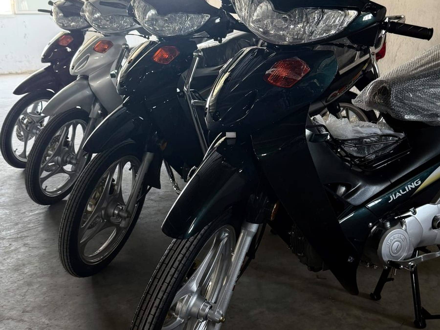 Rangée de motos Jialing neuves sous plastique d'usine dans le dépôt de l'importateur officiel à Ben Arous